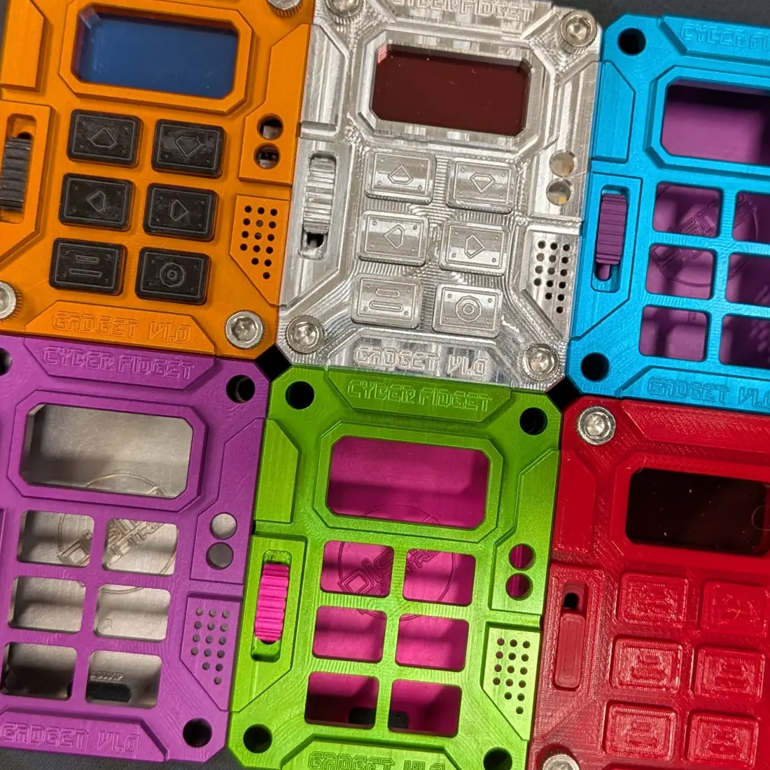 Six Cyber Fidget cases in anodized colorways around the raw aluminum original
